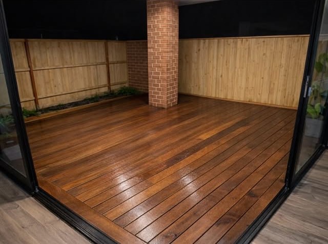 Hardwood deck running around a brick pillar under cover